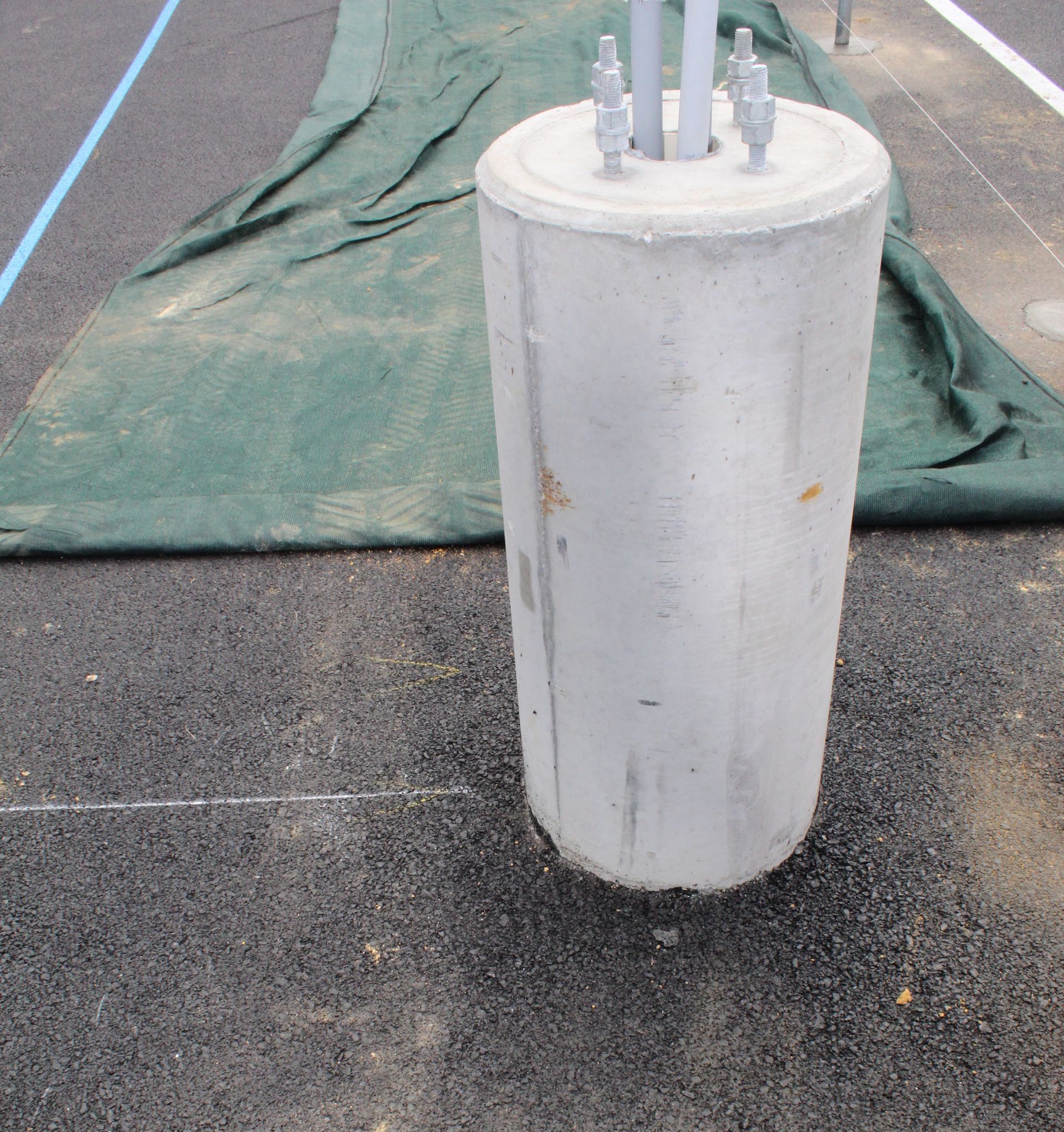 A large concrete cylinder is sitting on the ground next to a green tarp