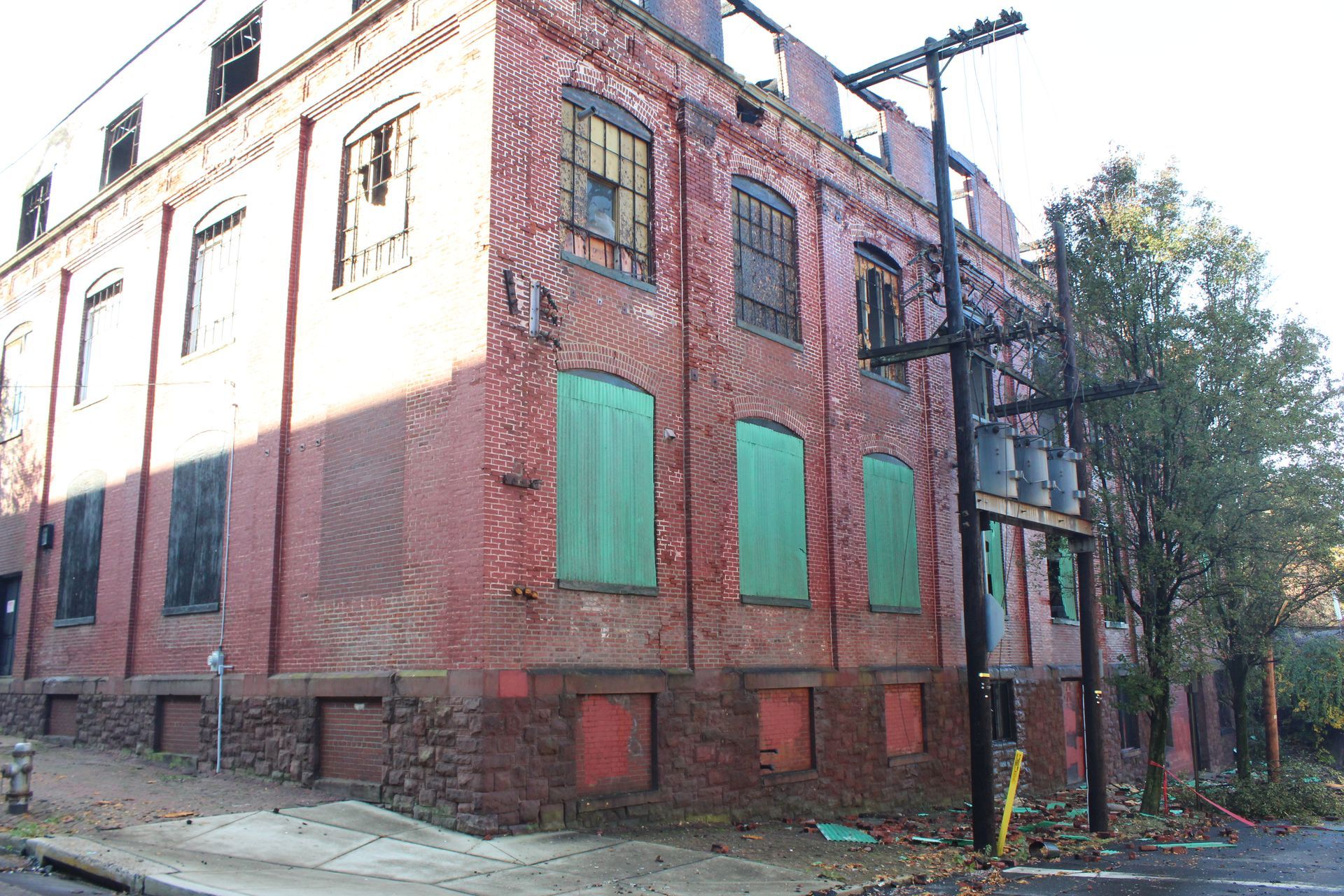 A brick building with green windows and a telephone pole in front of it