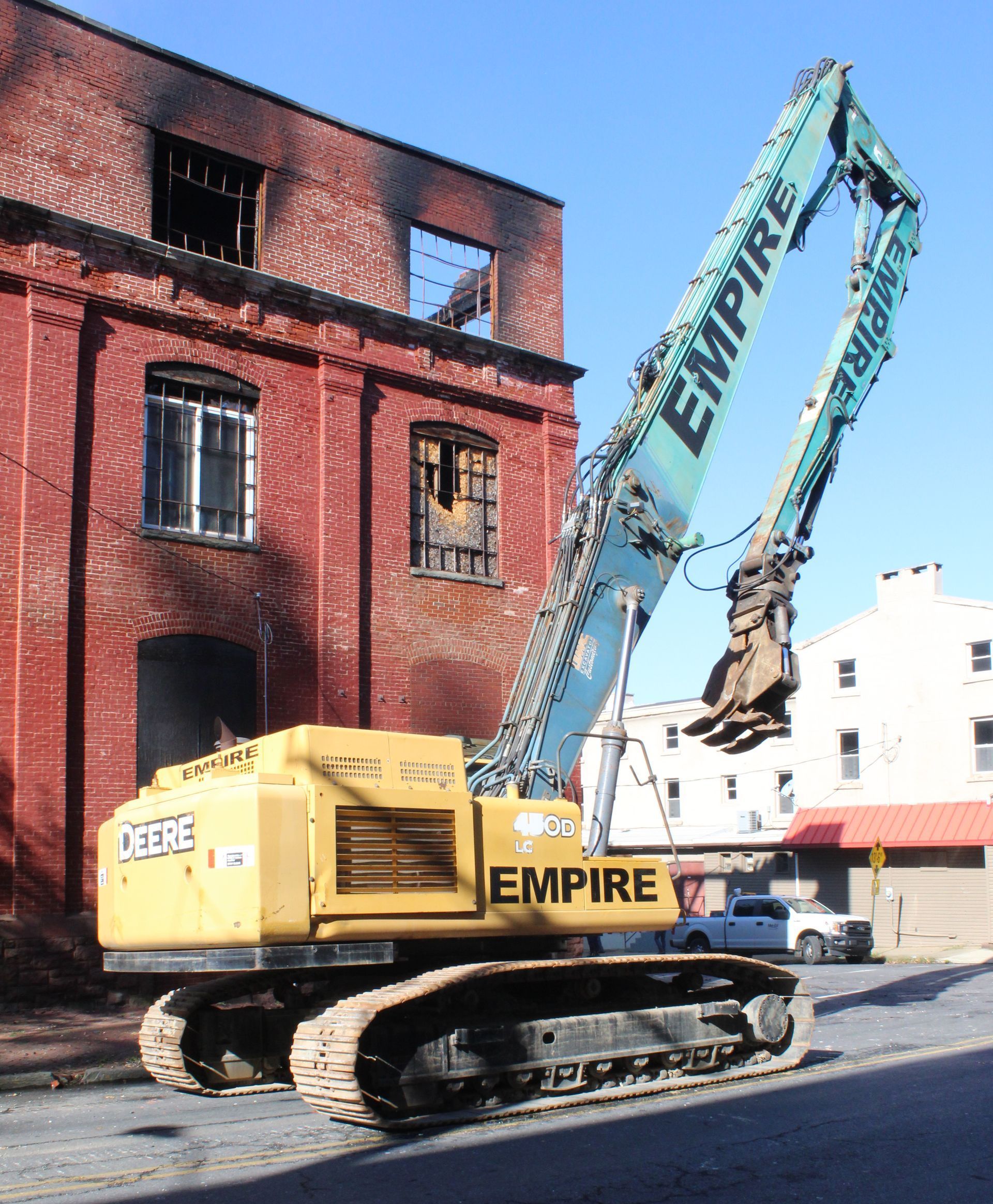 An empire excavator is parked in front of a brick building