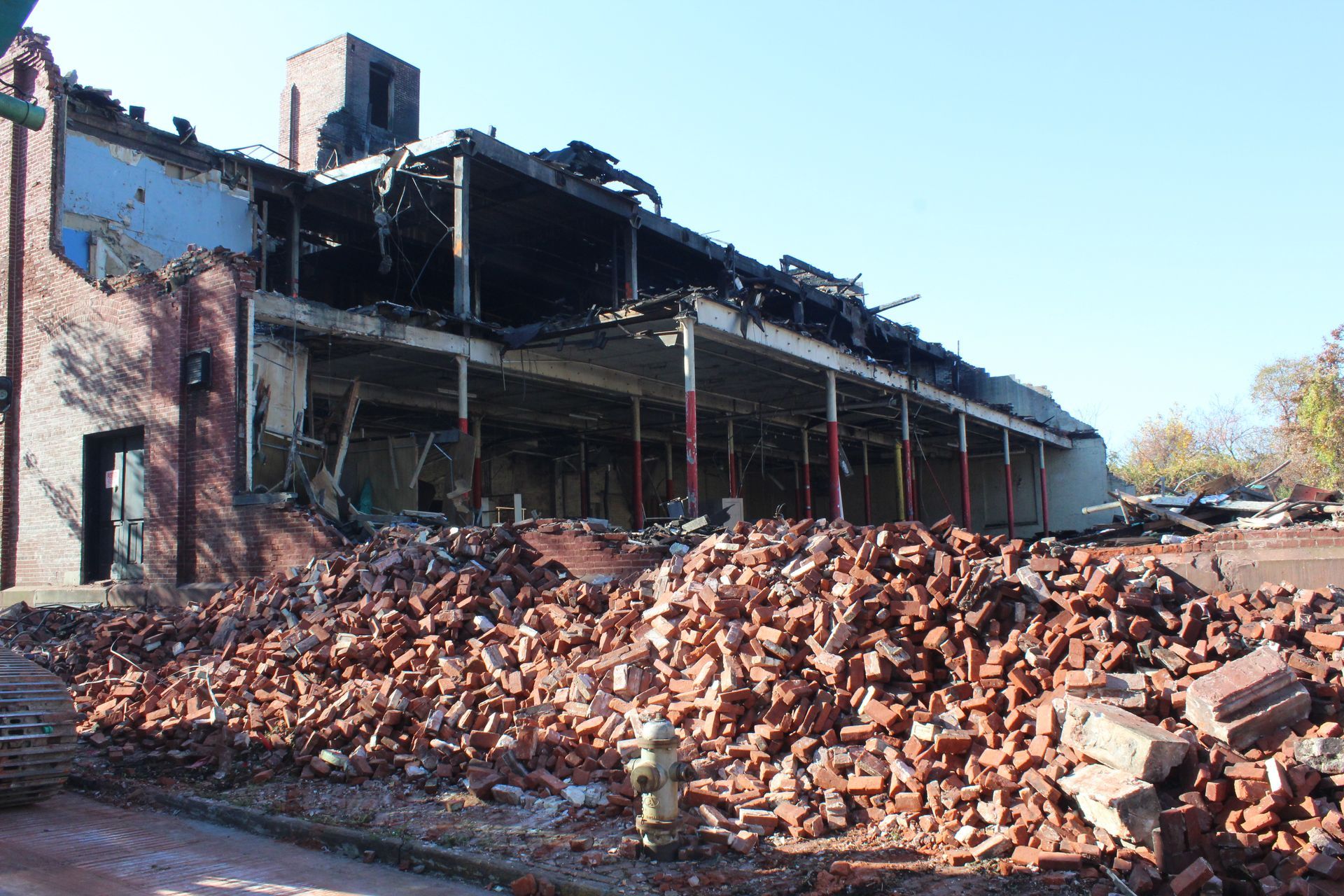 A large pile of bricks is sitting in front of a building that is being demolished.