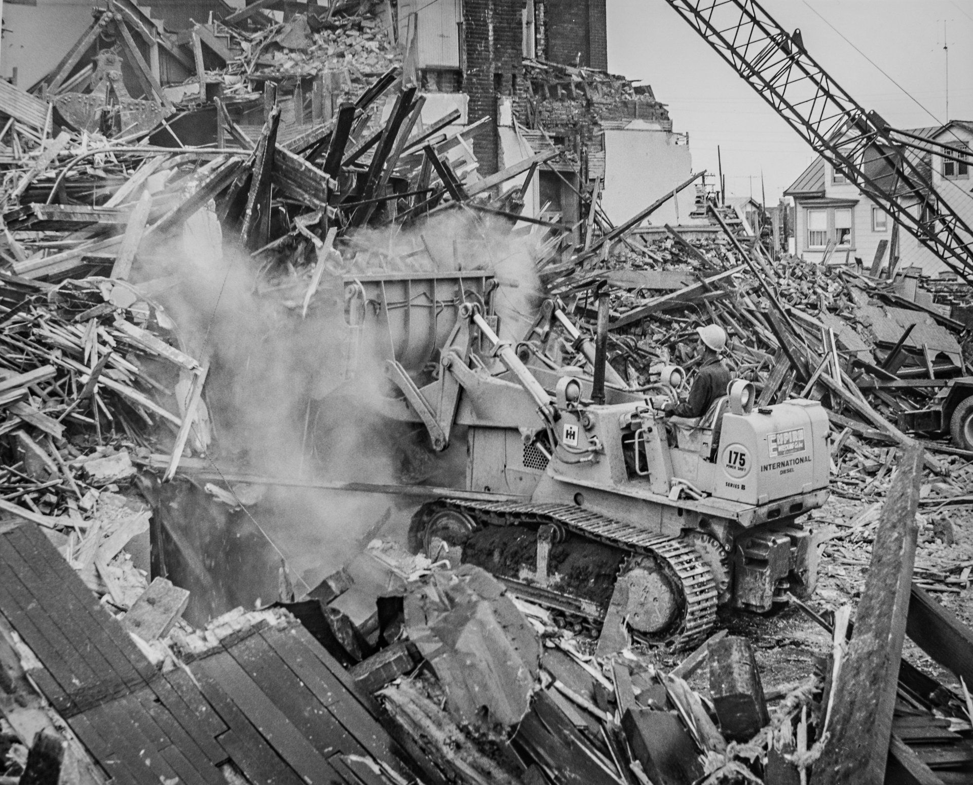 A black and white photo of a bulldozer demolishing a building