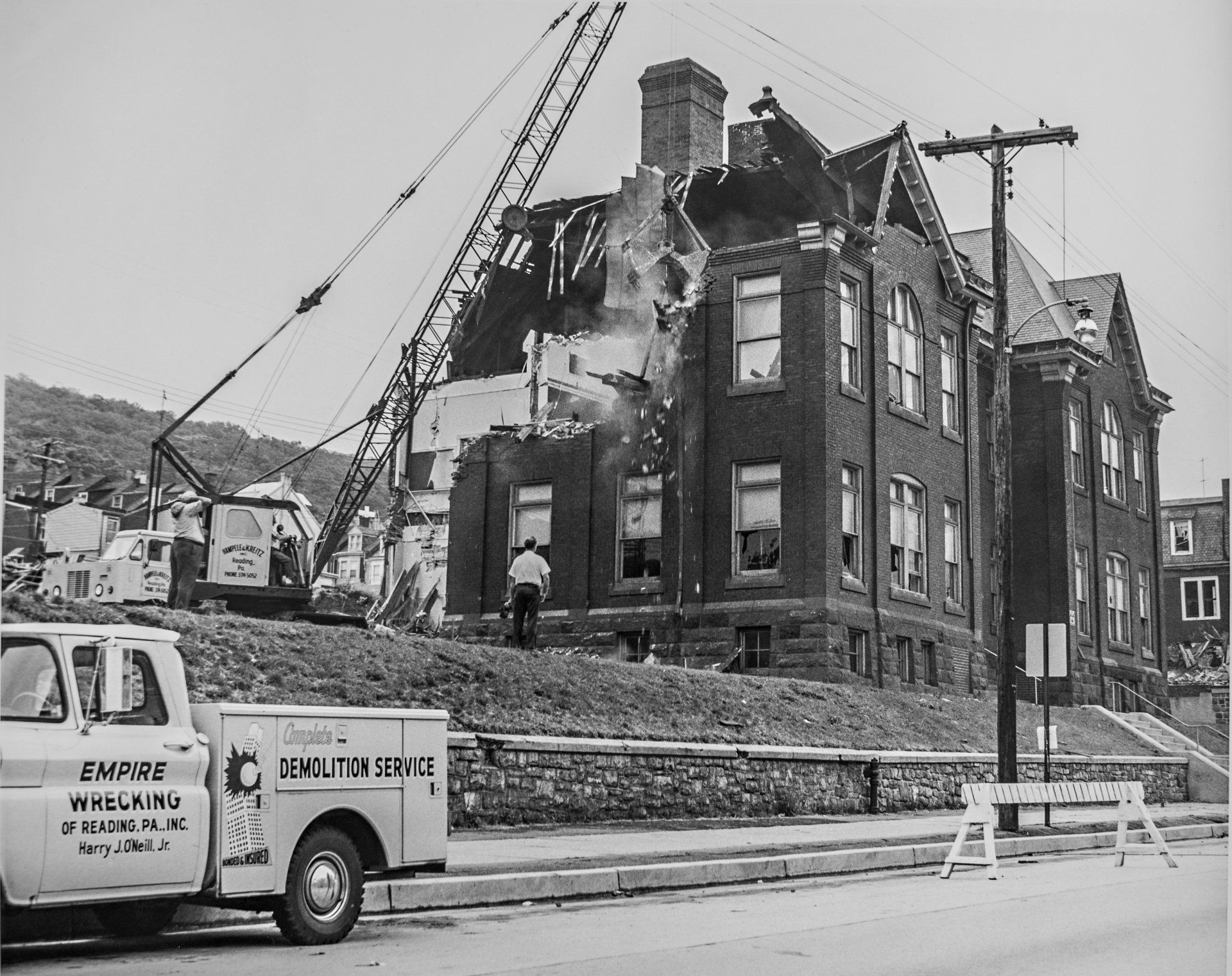 A demolition truck is parked in front of a brick building