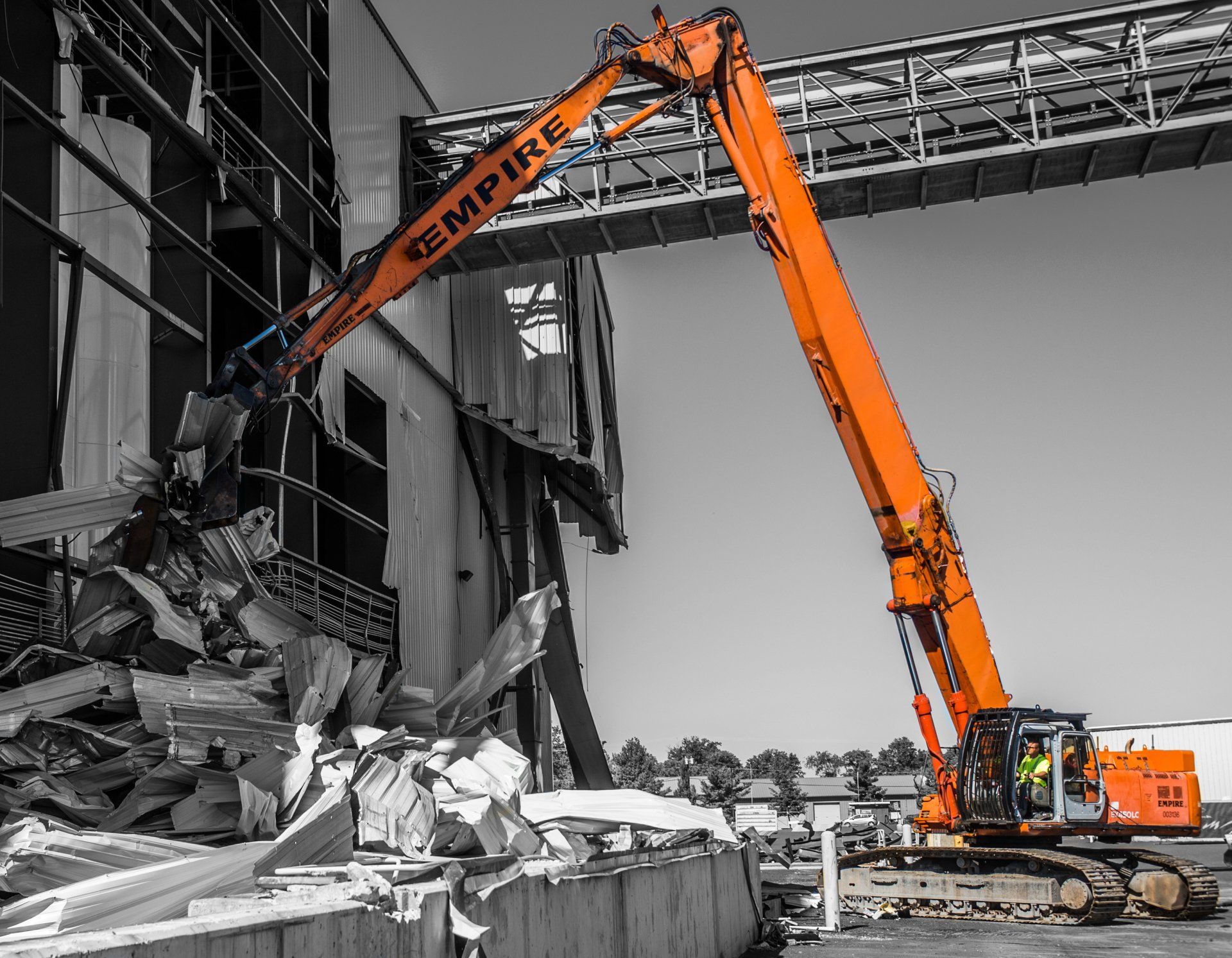 A large orange excavator is demolishing a building.