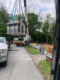 A crane is lifting a house into the air.