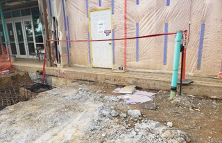 A construction site with a pipe in the dirt in front of a building.