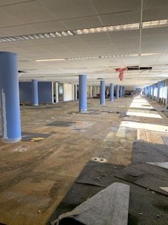 An empty building with a lot of columns and a lot of carpet on the floor.