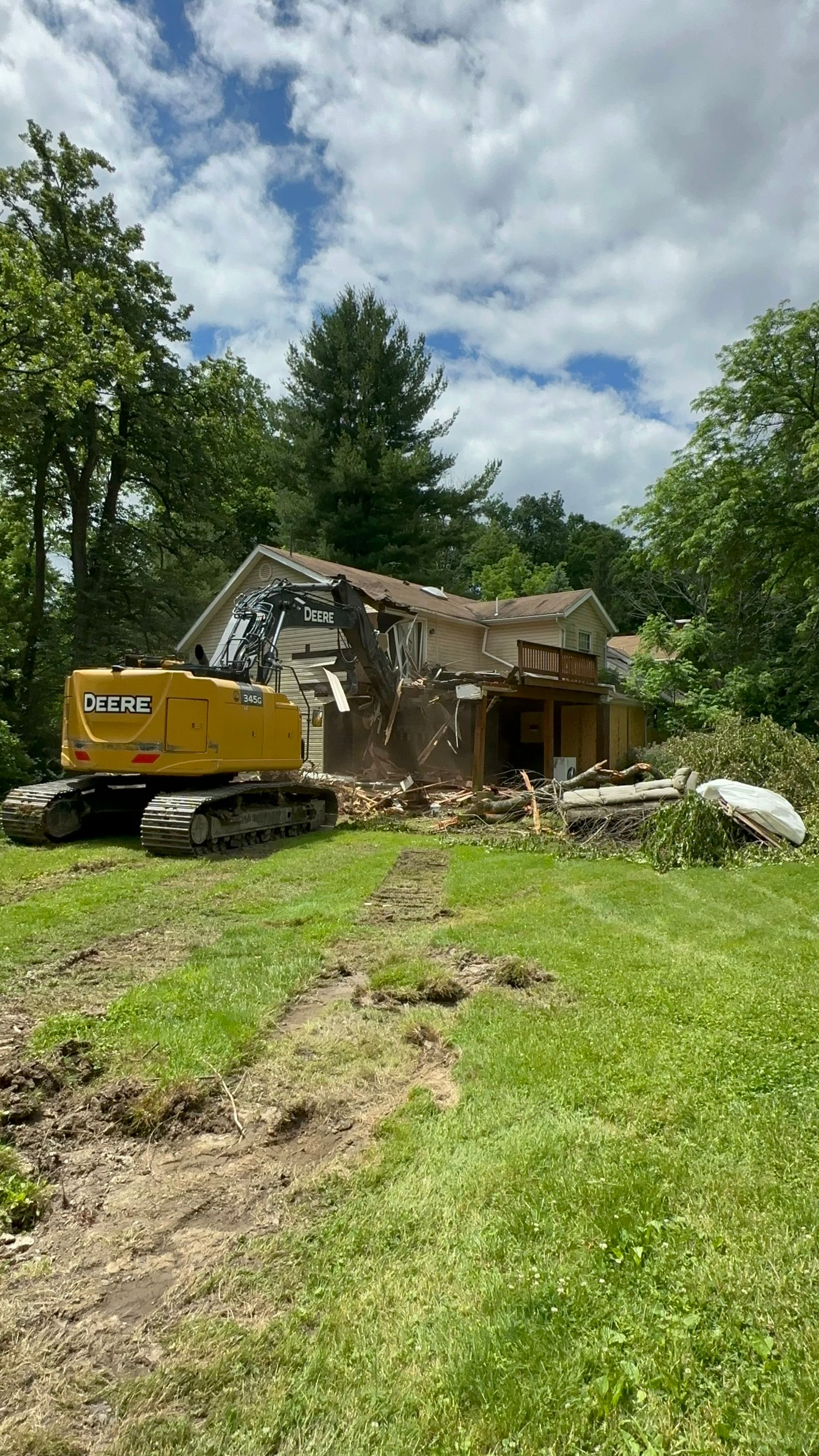 A large yellow excavator is demolishing a house.