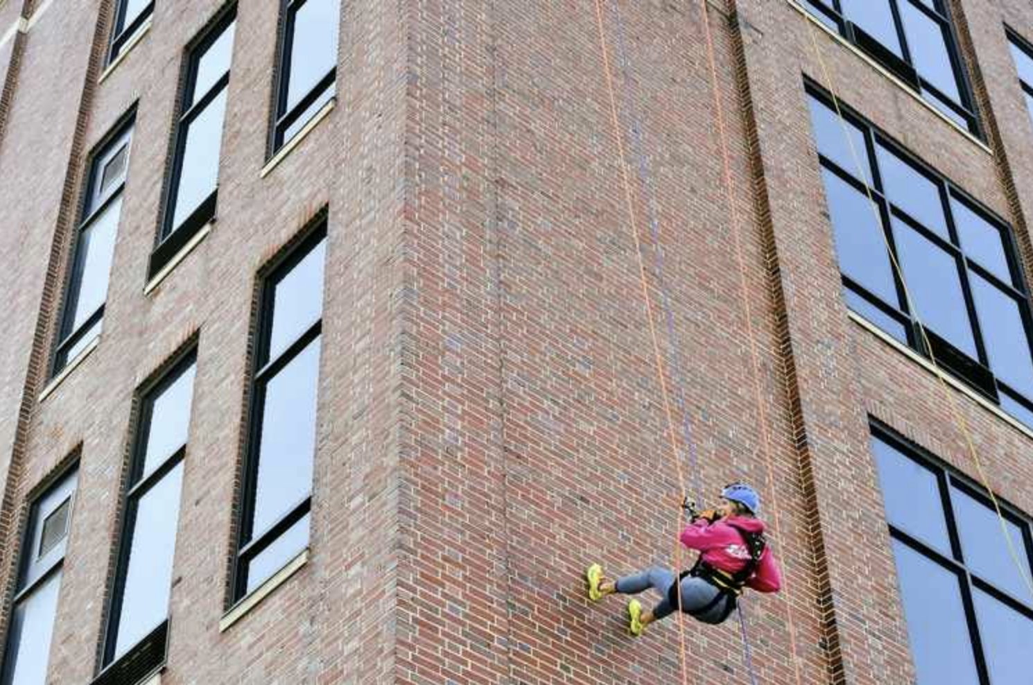 A person is climbing up the side of a brick building