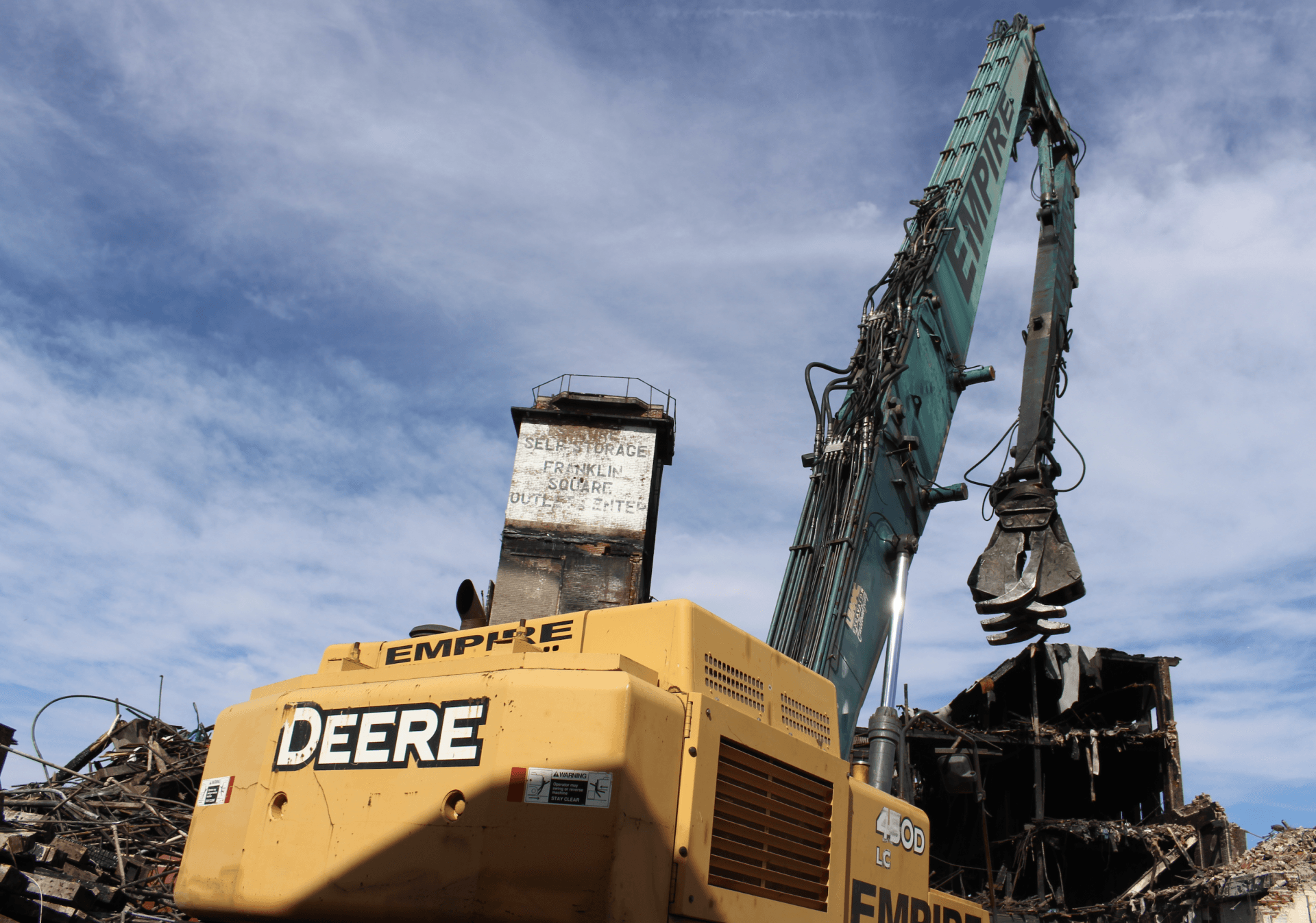 A yellow deere excavator is working on a pile of scrap metal