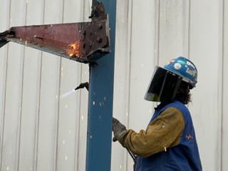 An Empire Services crew member dismantles the metal canopy frame using a flame torch.