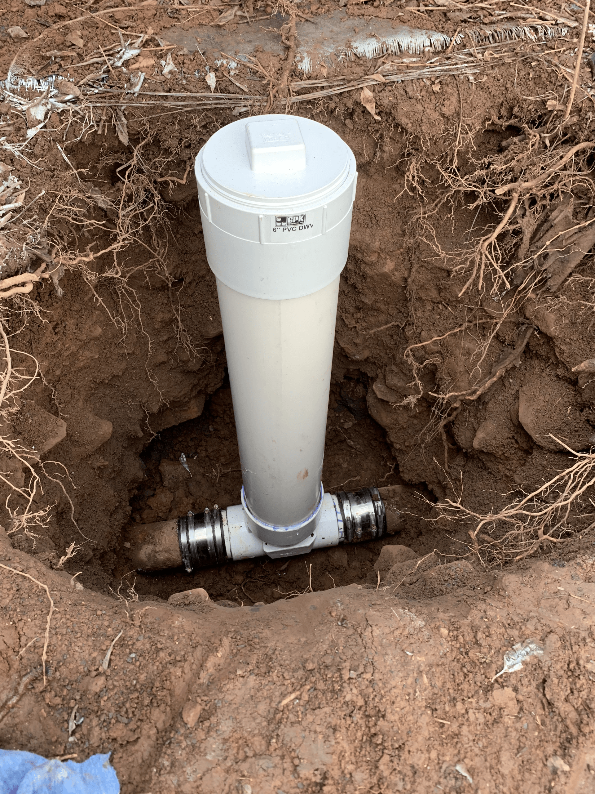 A white pipe is sitting in the middle of a hole in the ground.