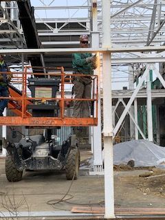 A man is standing on a lift working on a building.
