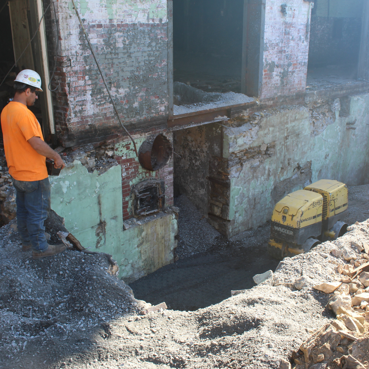 An Empire Services crew member operates a Wacker Neuson RT-82 trench roller via remote-control to compact the stone backfill.