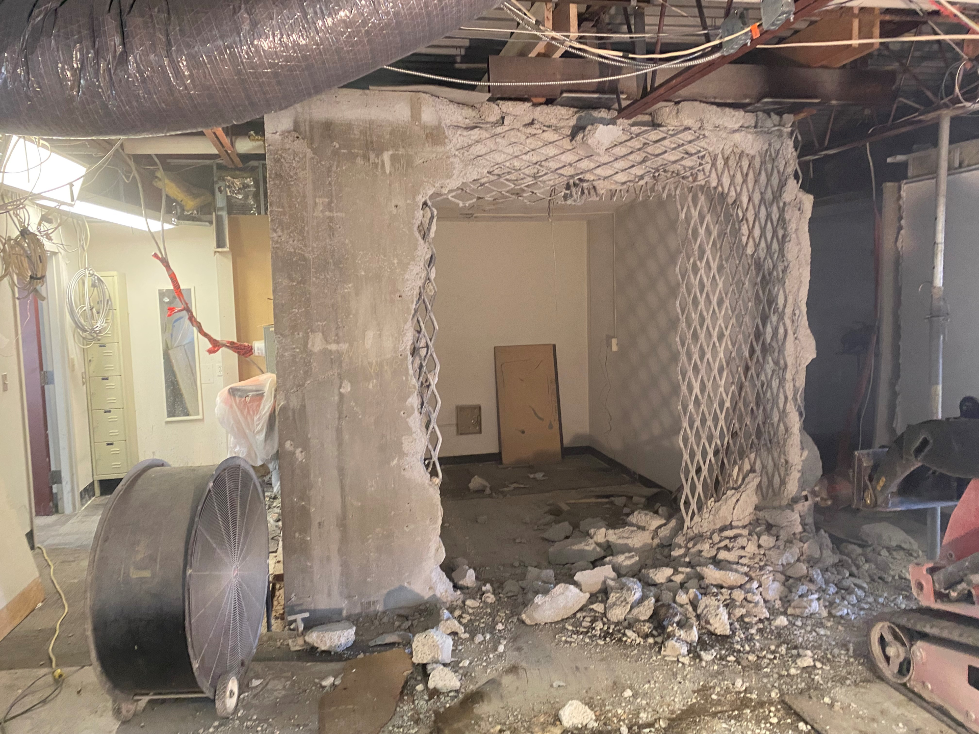 A concrete wall is being demolished in a room.