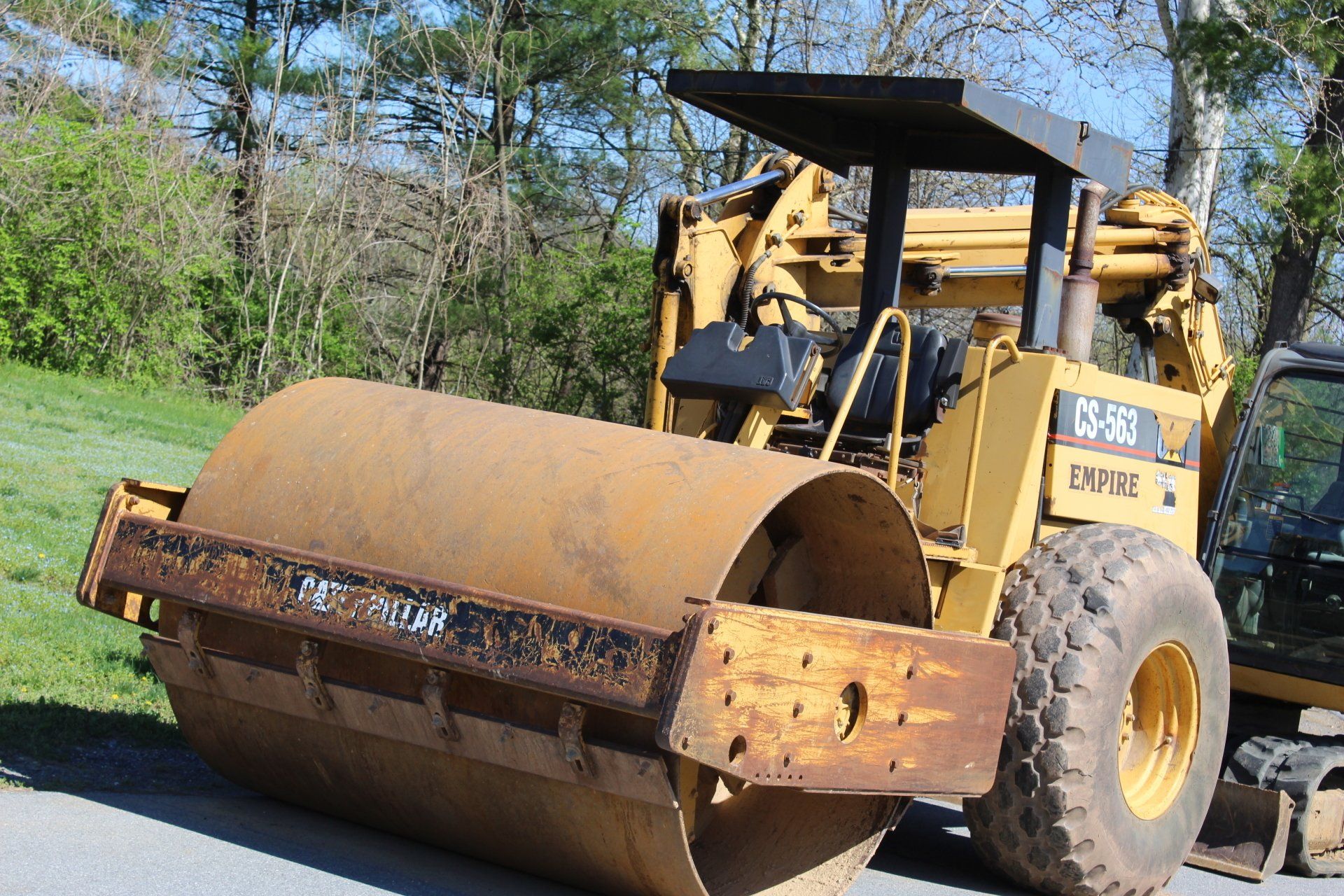 A large yellow roller is parked on the side of the road.
