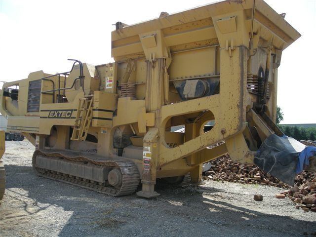 A large yellow excavator is parked in a gravel lot
