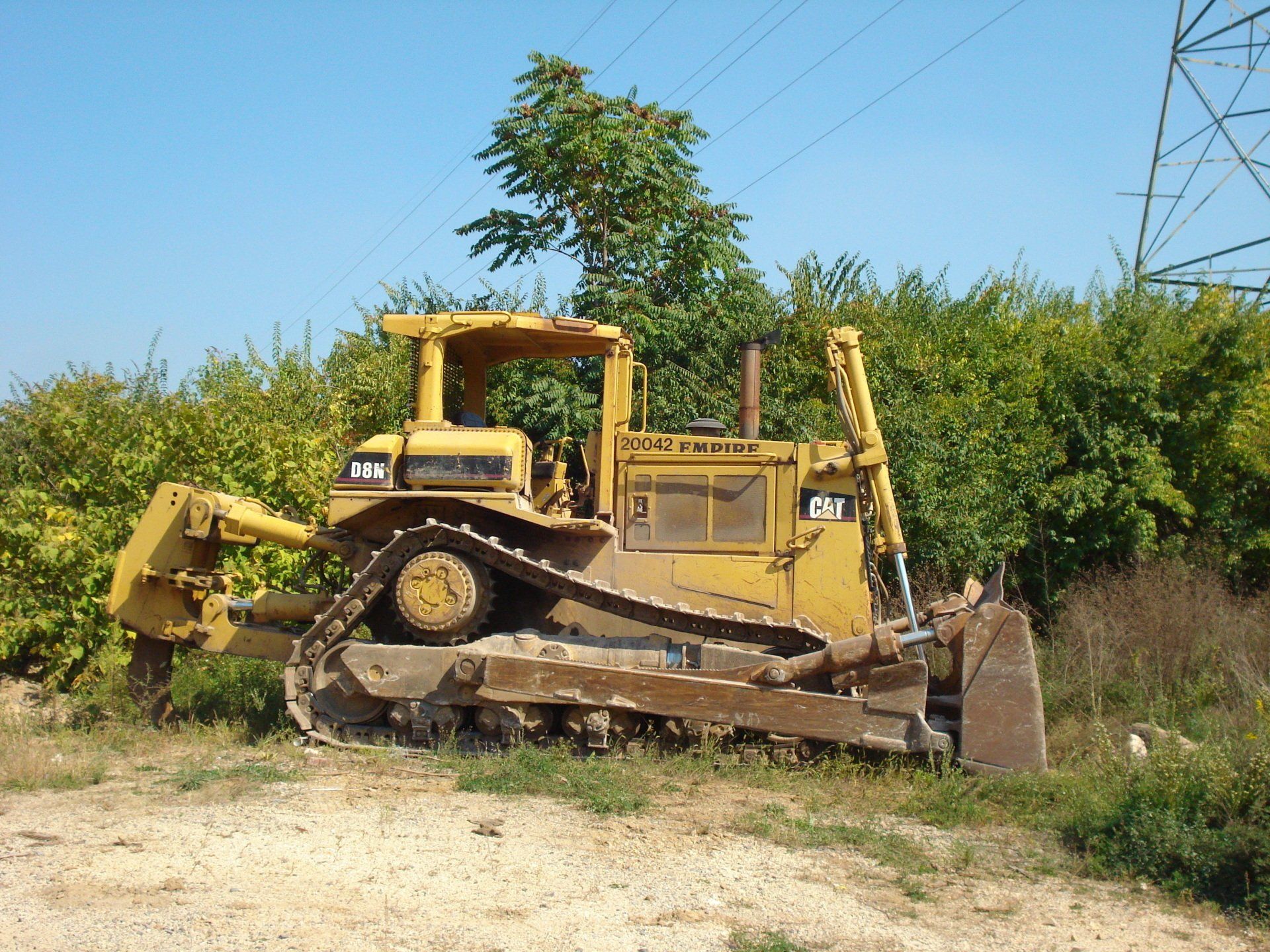 A yellow caterpillar bulldozer is parked in a field