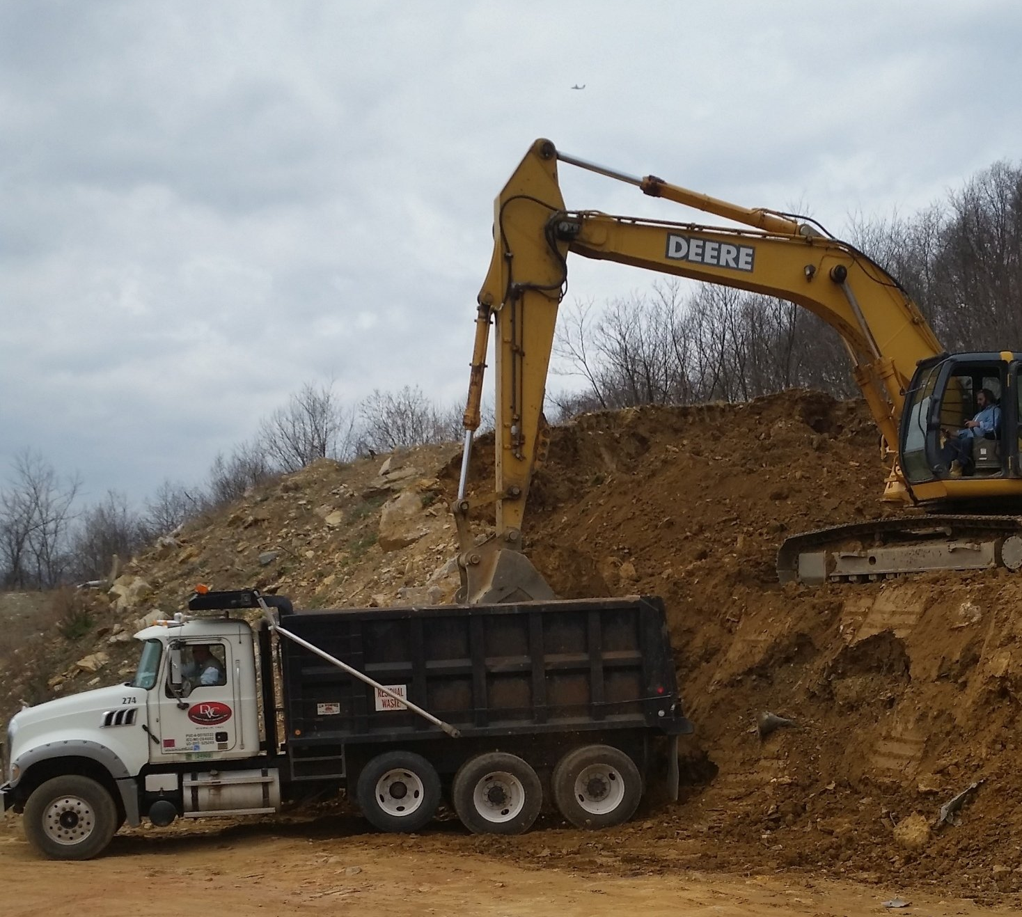 A deere excavator is loading dirt into a dump truck