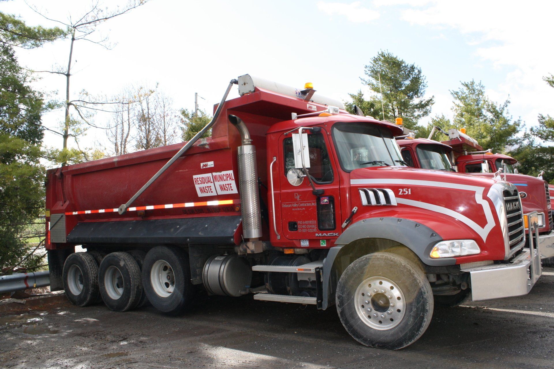 A red dump truck is parked in a gravel lot.