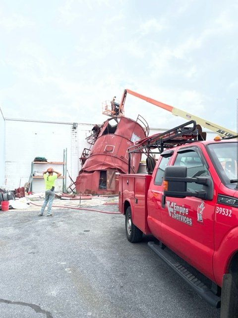 A red truck is parked in front of a building that is being demolished.