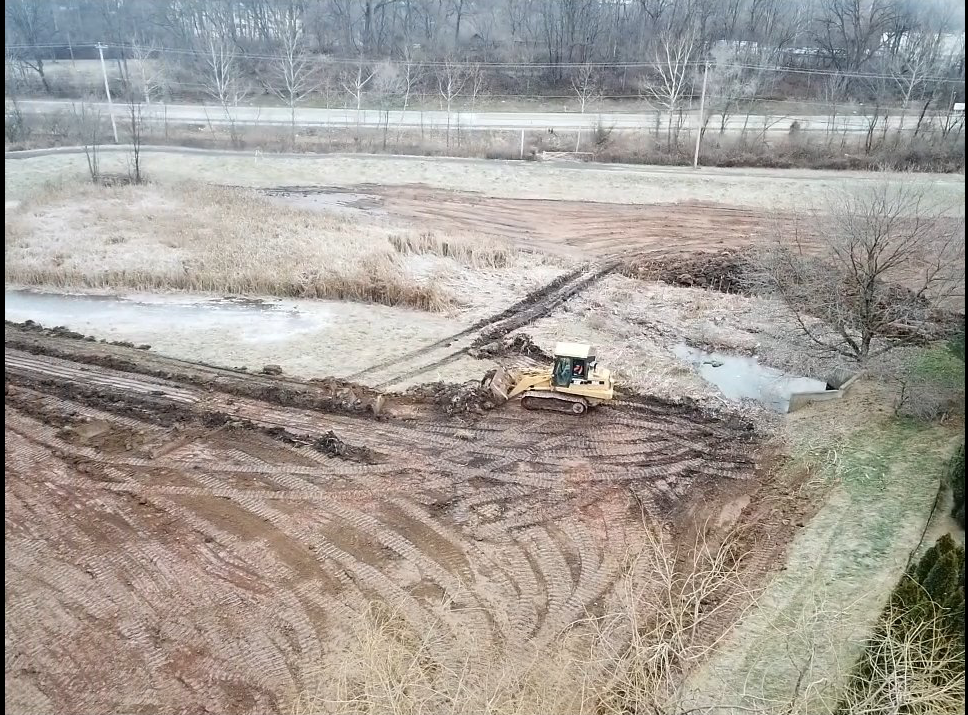 An aerial view of a bulldozer moving dirt in a field.