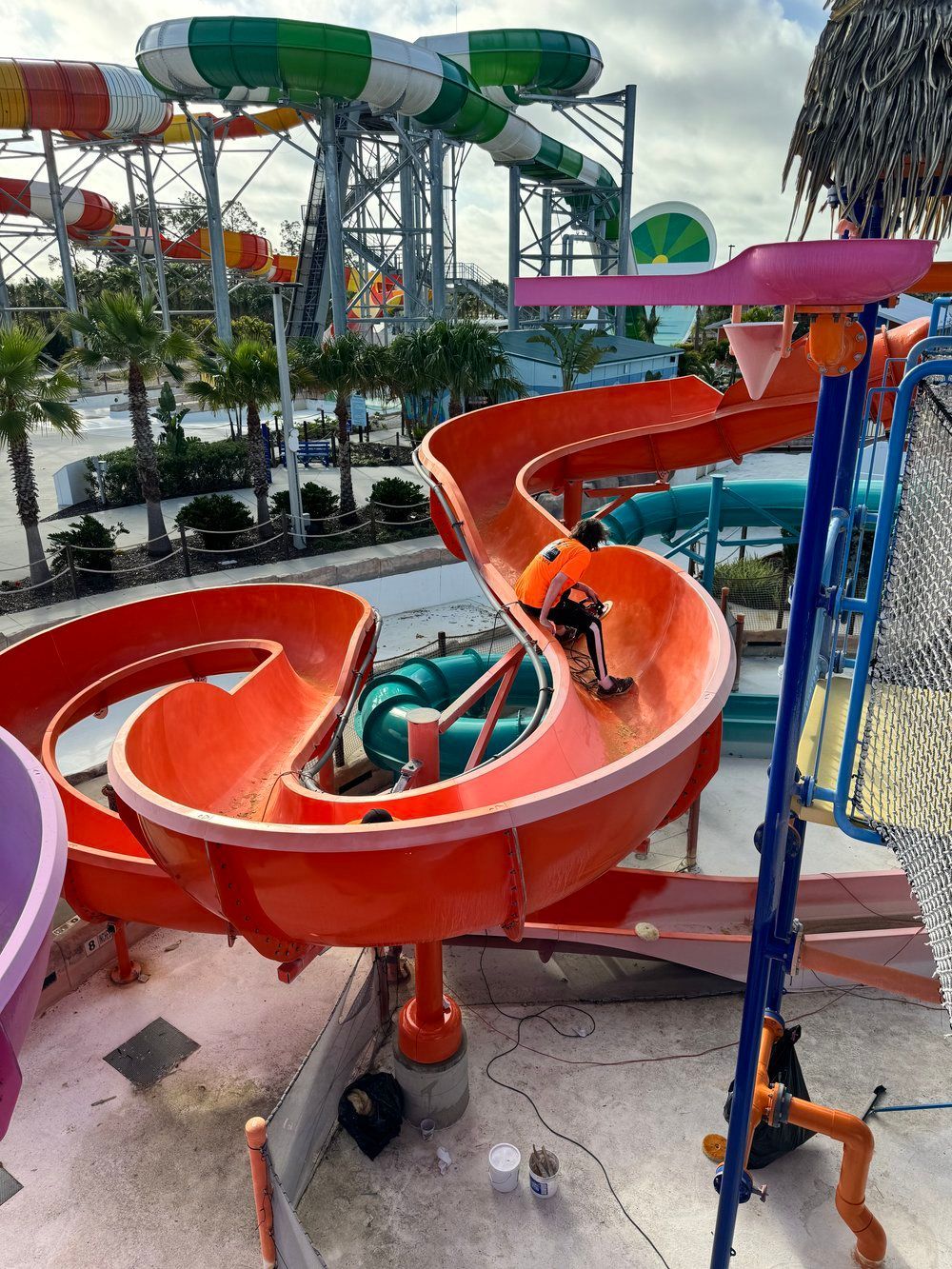 Team installing bright orange fiberglass waterslide at waterpark