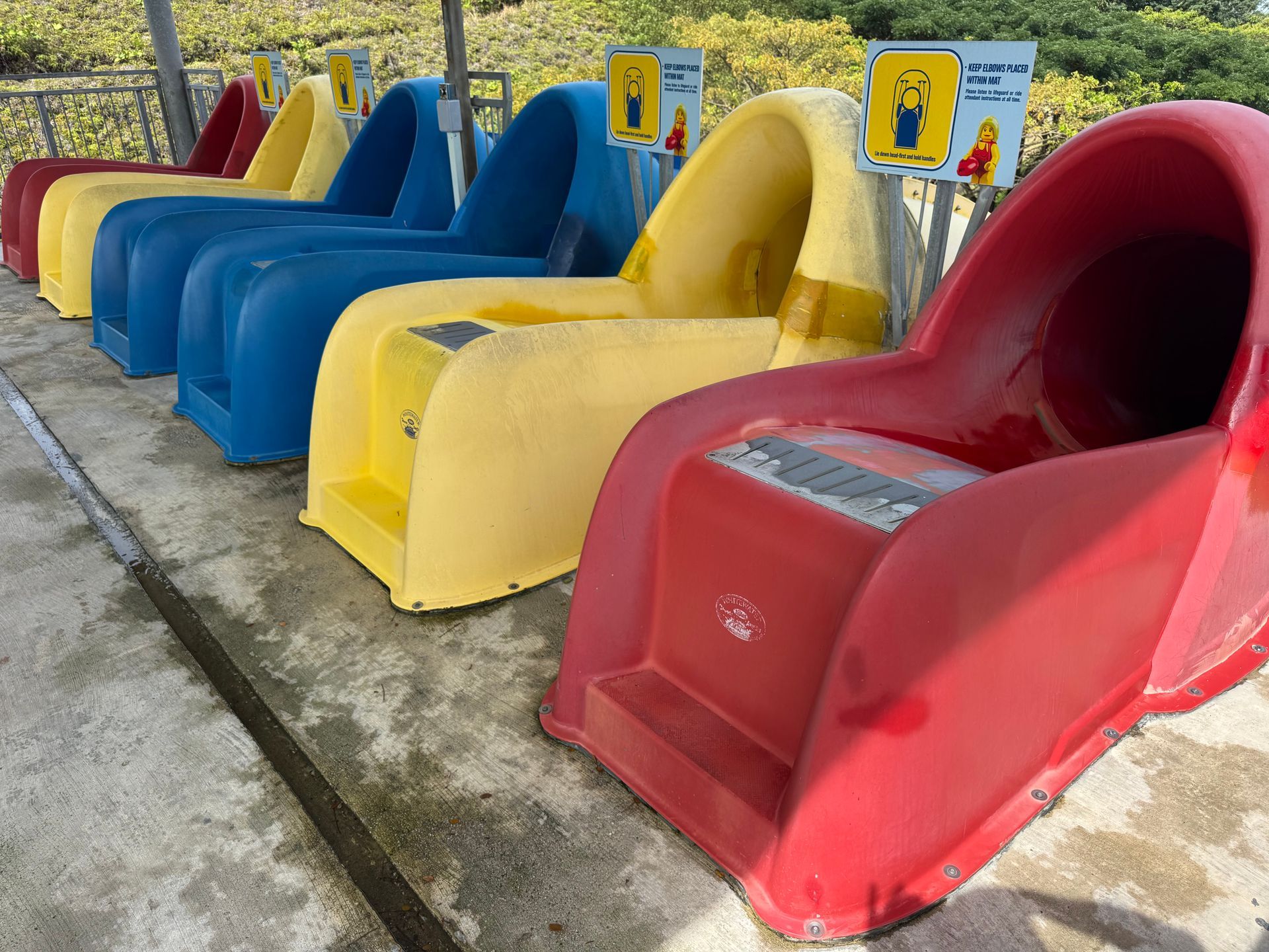 Red, yellow, and blue waterslide launch chutes at Legoland Malaysia showing surface wear before restoration