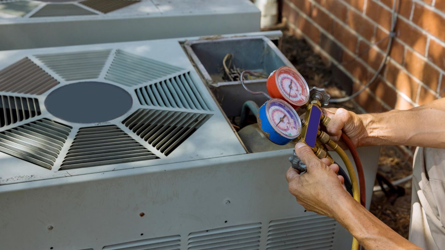 Person using gauges on an outdoor air conditioning unit.