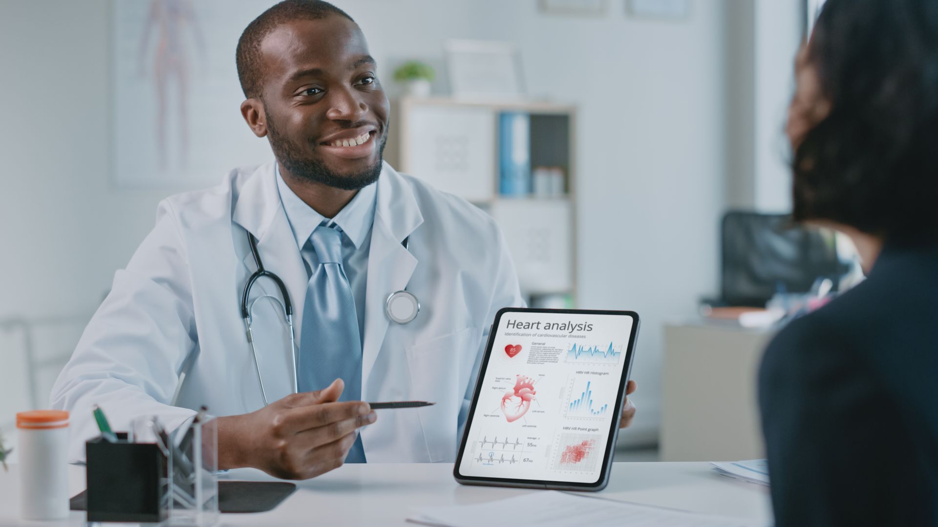 Doctor sitting behind desk holding a tablet.