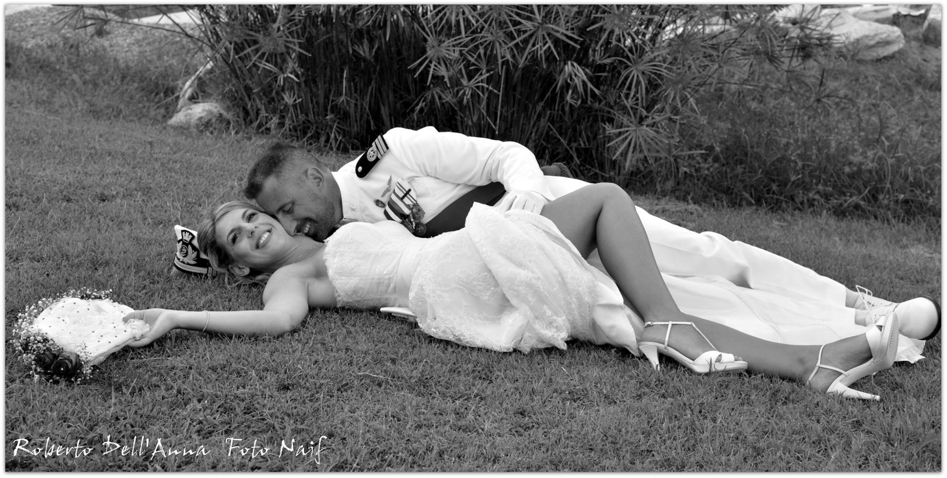 Una foto in bianco e nero di una sposa e uno sposo sdraiati sull'erba.