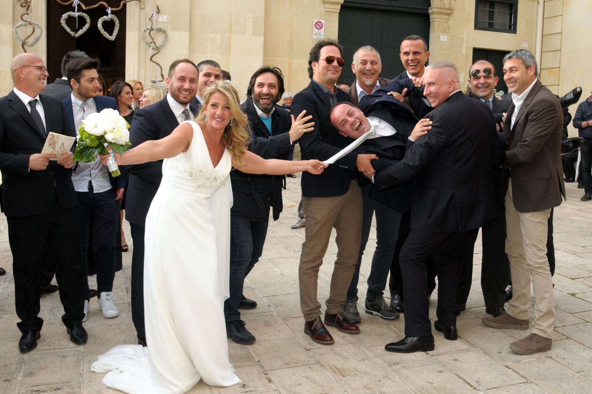 Una sposa e uno sposo posano per una foto con il loro corteo nuziale