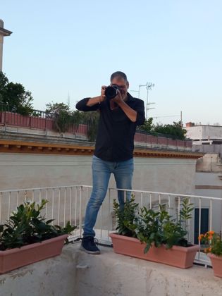 Un uomo in piedi su un balcone che scatta una foto con una macchina fotografica