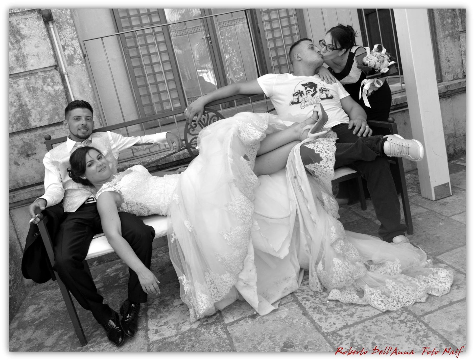 Una foto in bianco e nero di una sposa e uno sposo seduti su una panchina.
