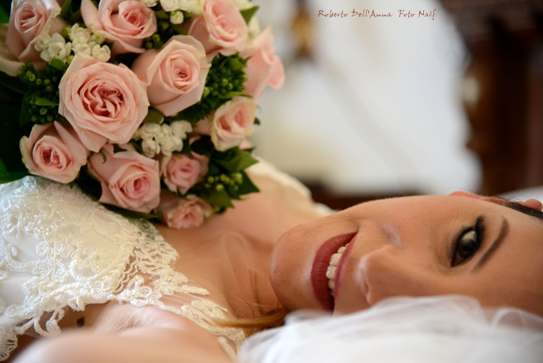 Una sposa è sdraiata su un letto con un mazzo di rose rosa.