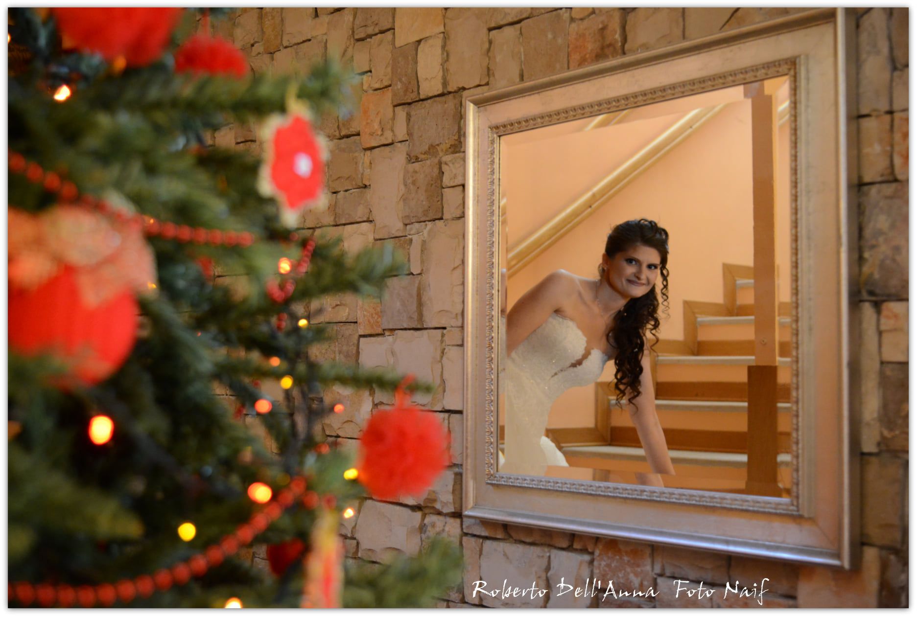 Una donna in abito da sposa si guarda allo specchio davanti all'albero di Natale