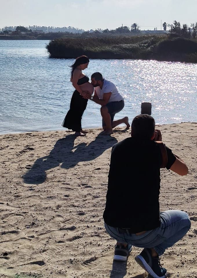 Un uomo sta scattando una foto a una donna incinta sulla spiaggia