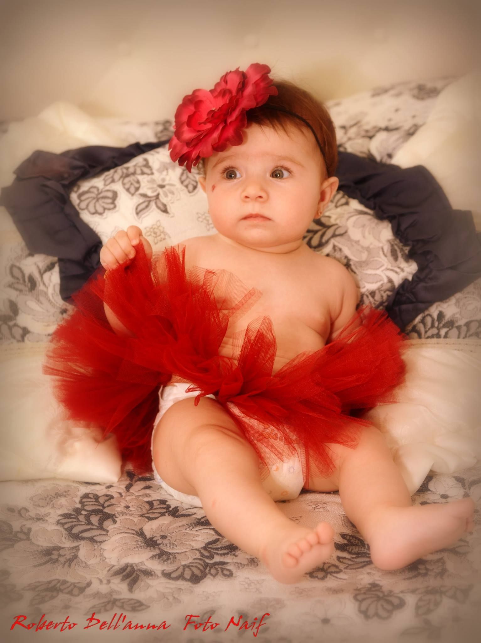 Un bambino che indossa un tutù rosso è seduto su un letto.