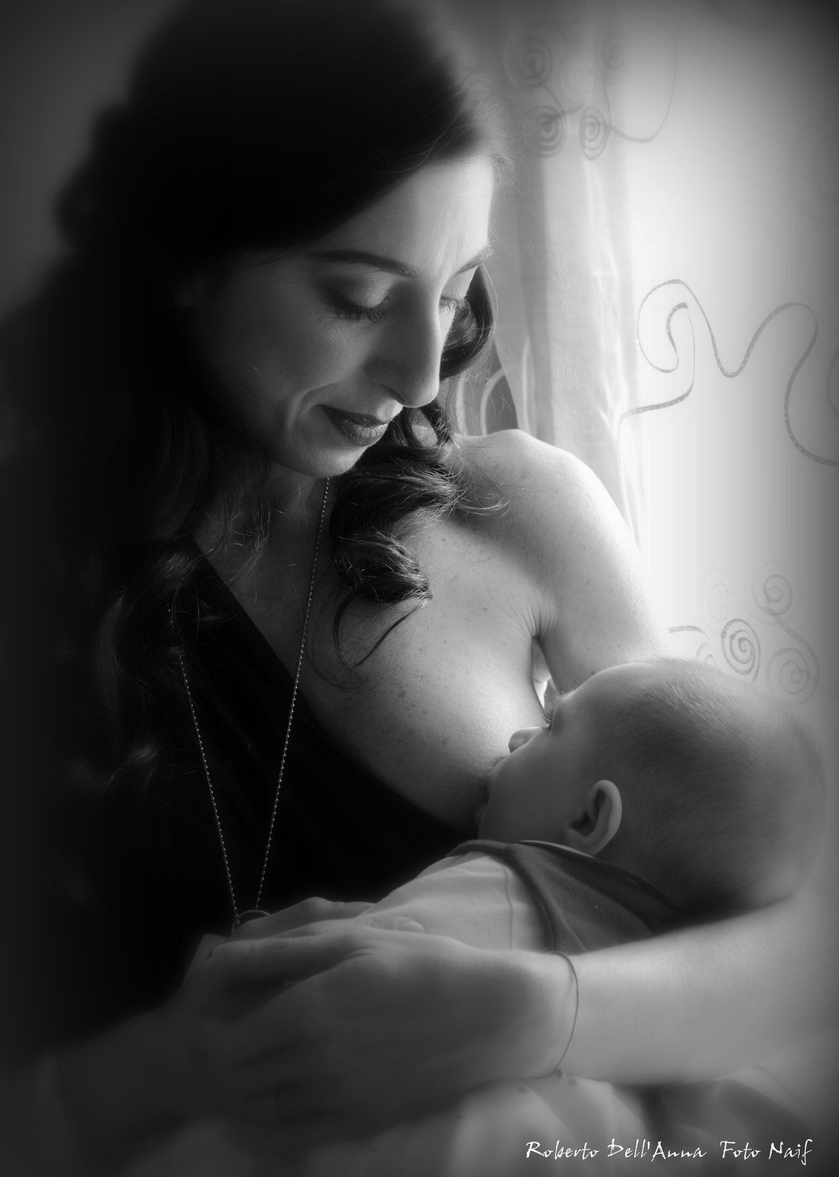 Una donna allatta il suo bambino in una foto in bianco e nero.