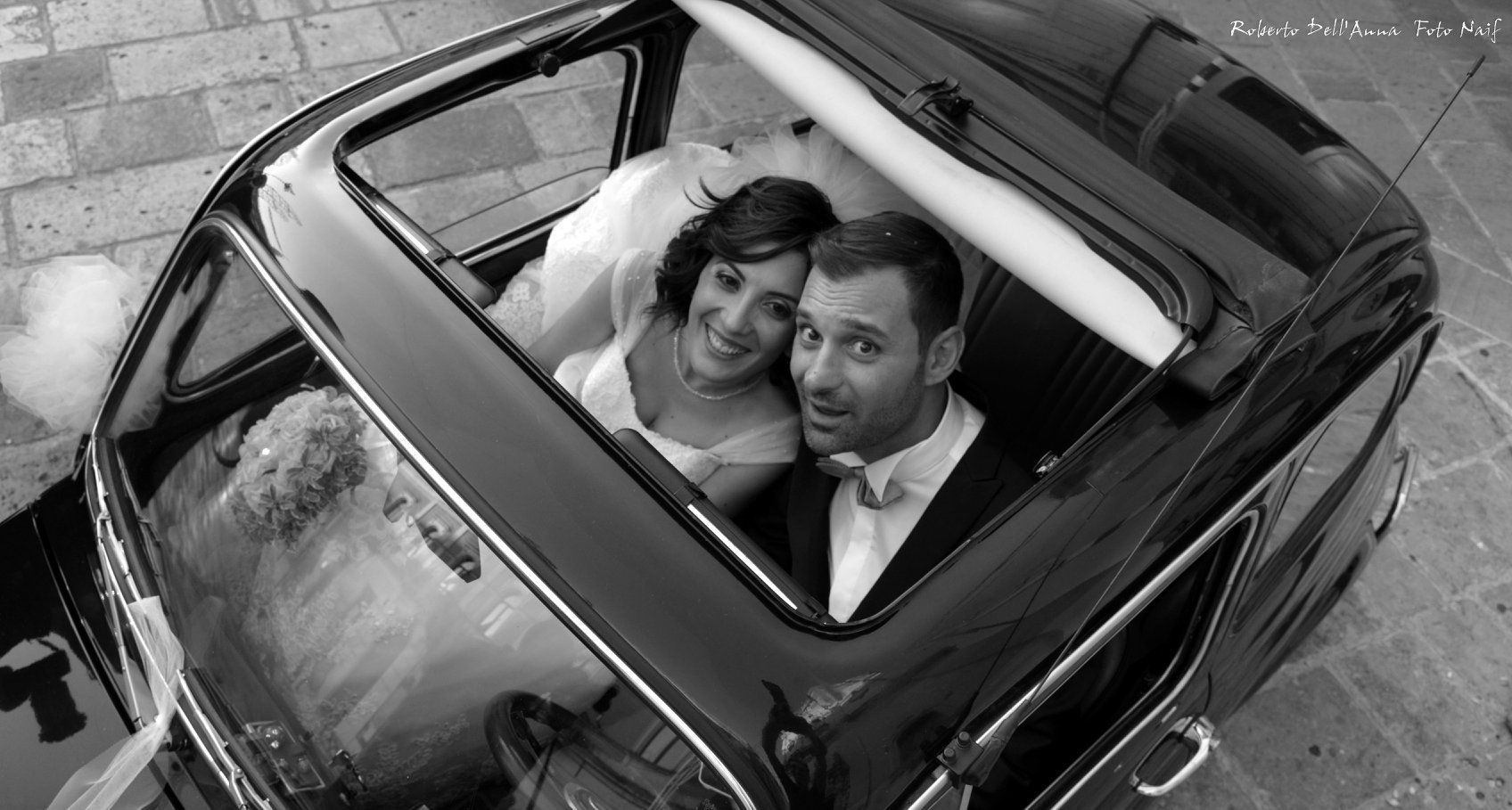 Una foto in bianco e nero di una sposa e uno sposo in macchina