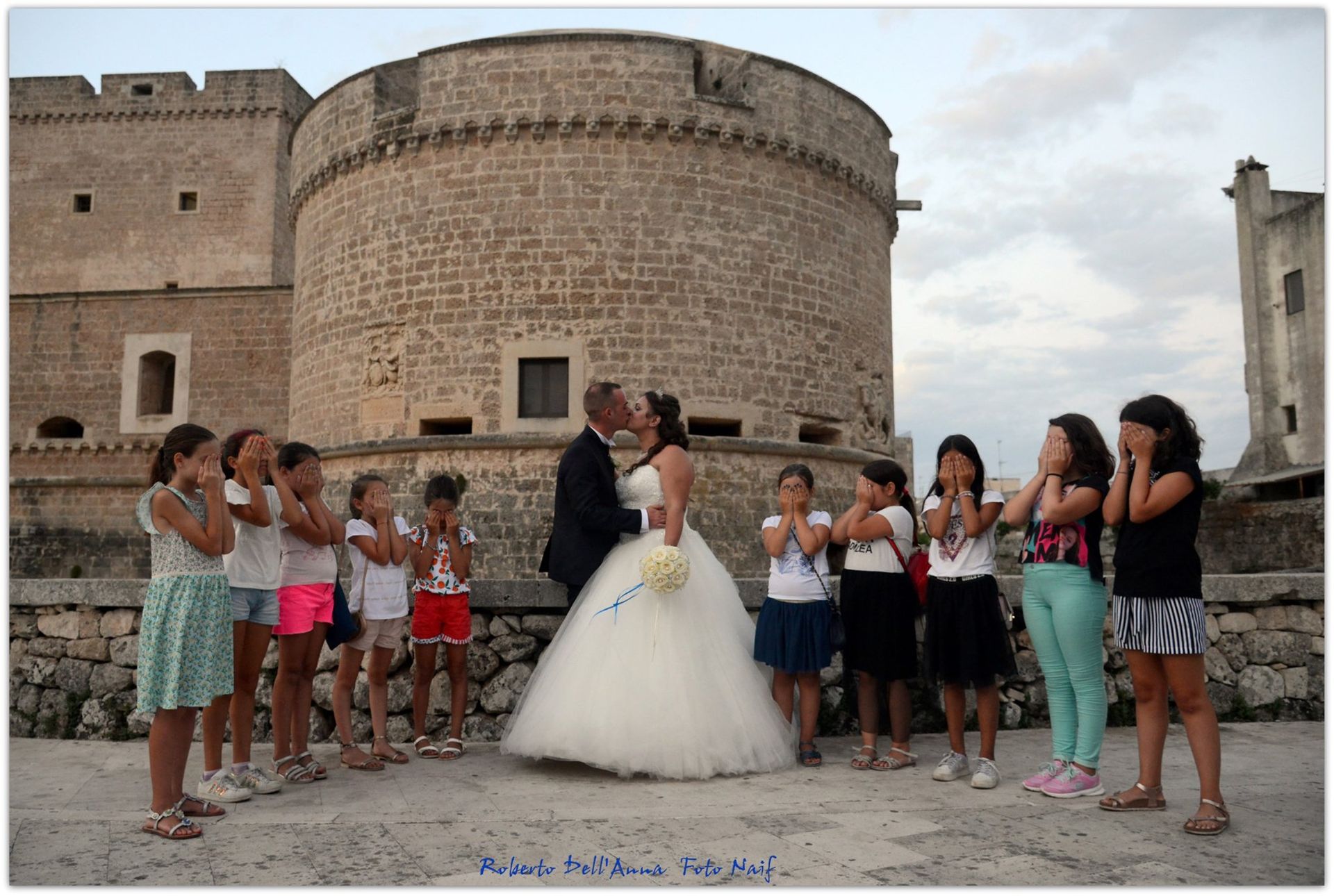 Una sposa e uno sposo che si baciano davanti a un castello