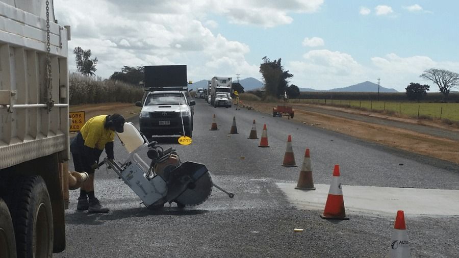 A Man Is Using A Machine To Cut A Hole In The Road — The Cairns Boyz In Manunda, QLD