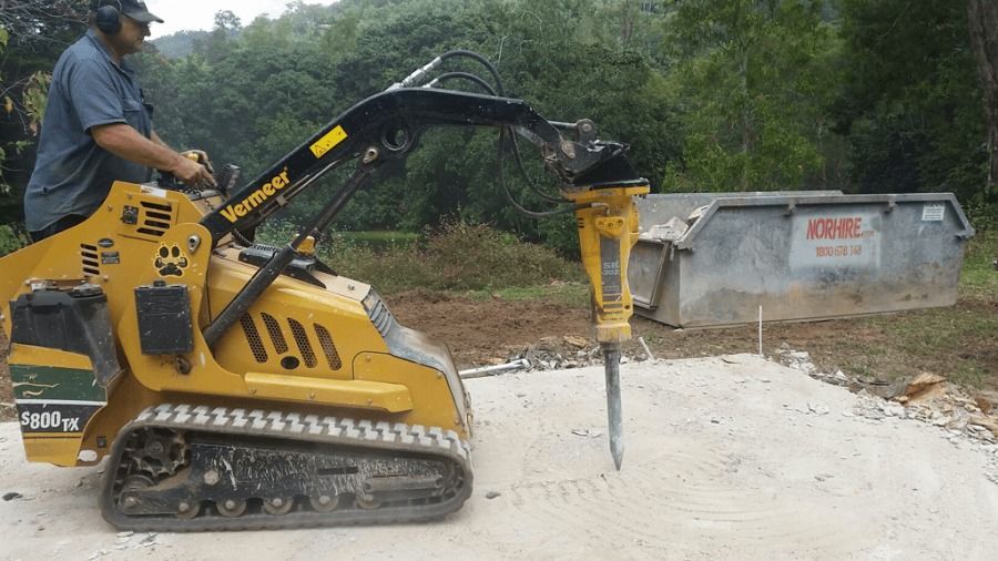 A Man Is Driving A Tractor With A Hammer Attached To It — The Cairns Boyz In Manunda, QLD