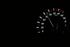 A close up of a speedometer on a black background.