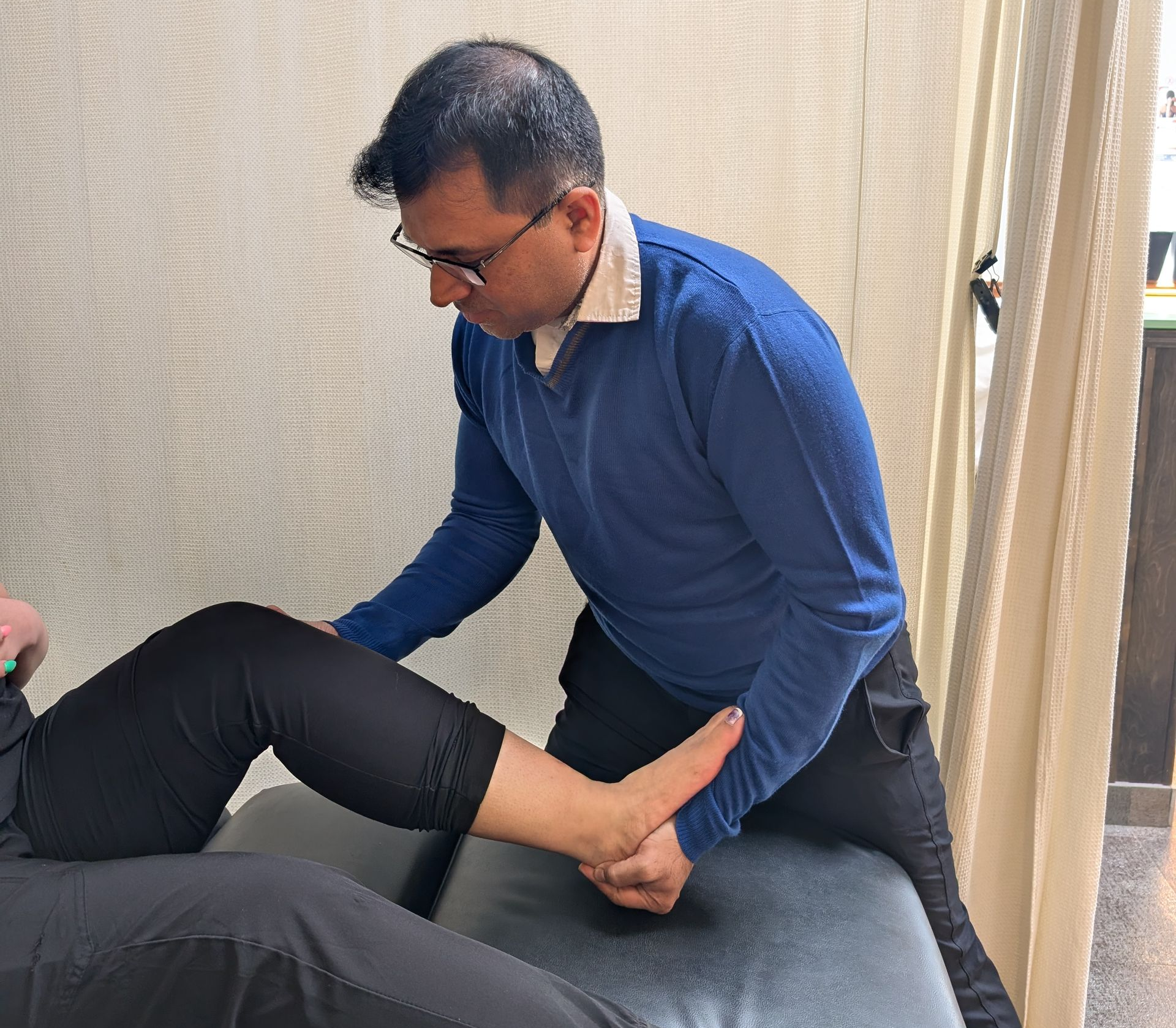 A nurse is helping an elderly man walk in a living room.