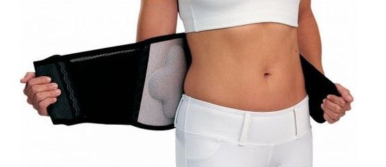 A nurse is helping an elderly man walk in a living room.