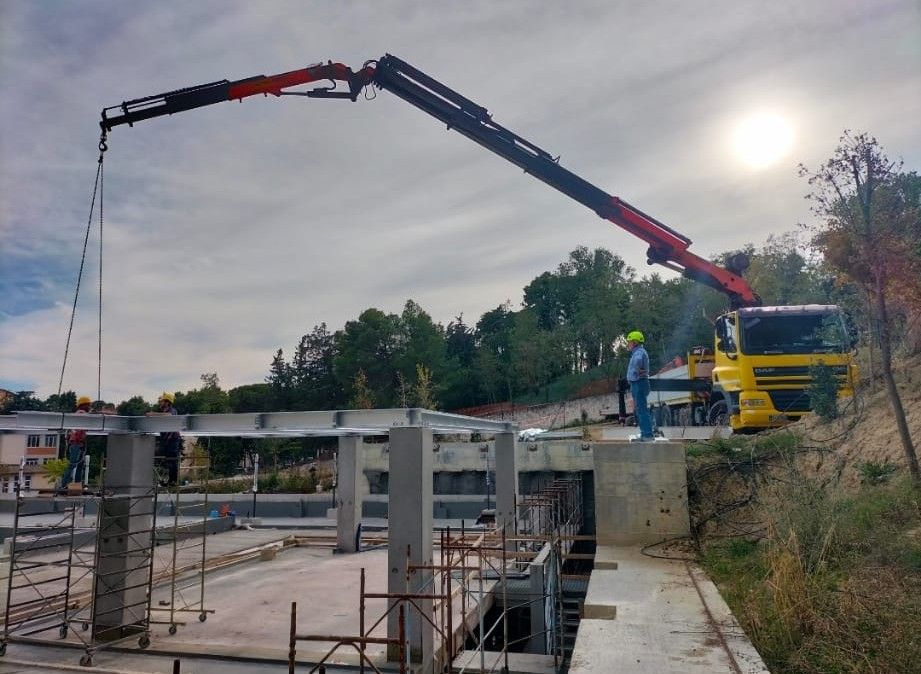 Autobetoniera che effettua il getto di calcestruzzo in un cantiere edile accanto alla struttura di un edificio.