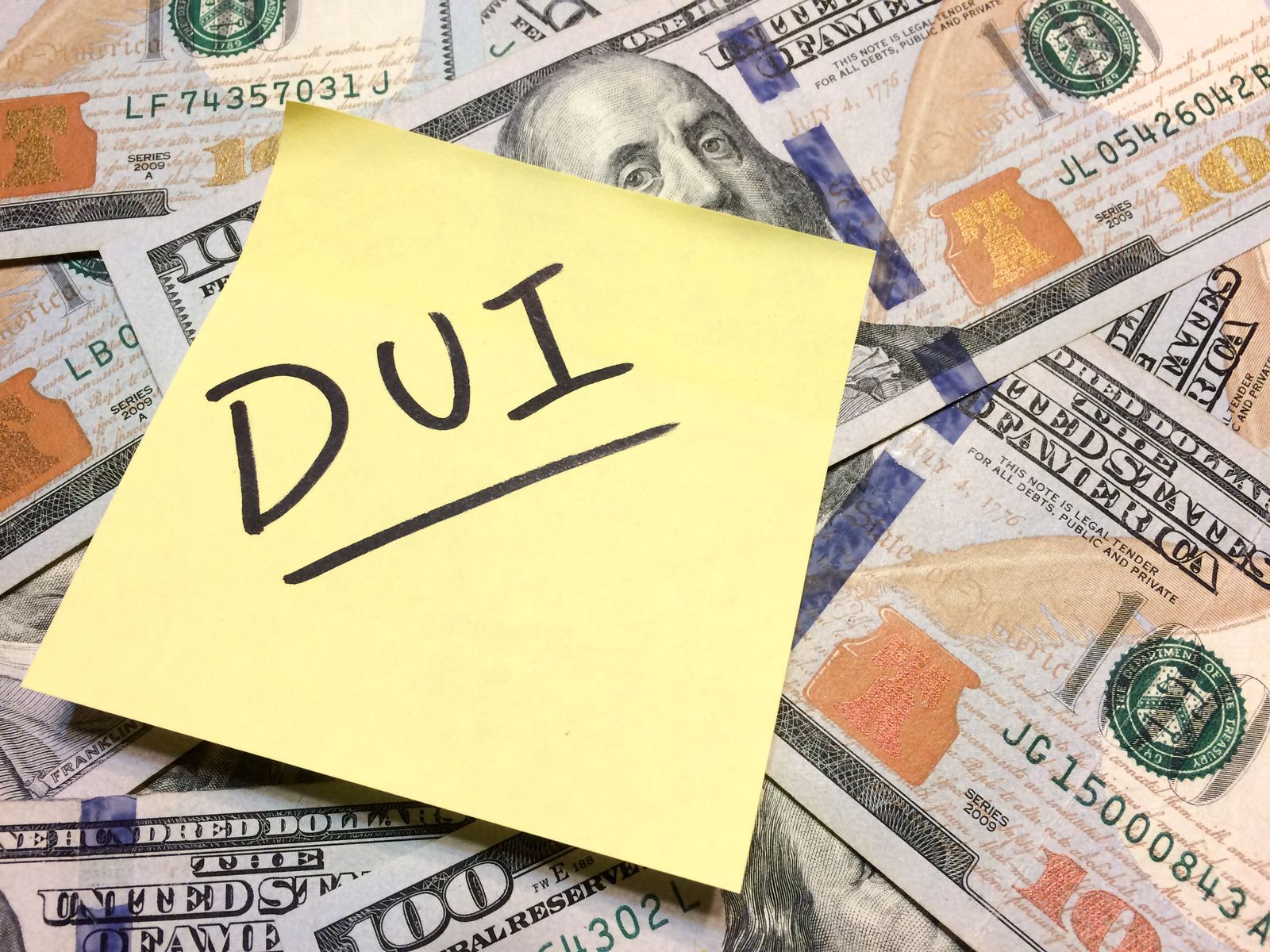 A sticky note with the word dui written on it is sitting on top of a pile of money.