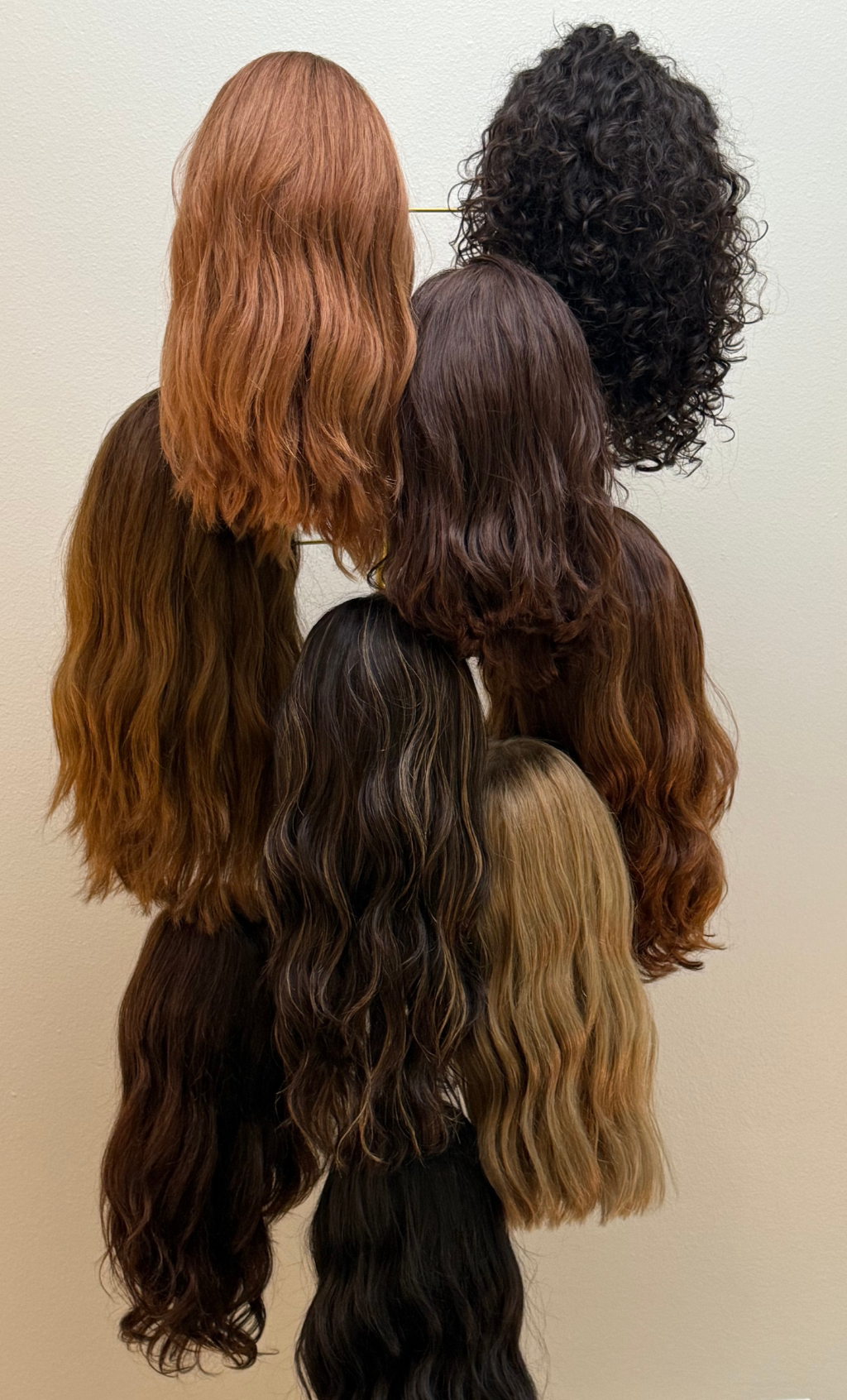 Wigs in various shades of brown and black hanging on a rack.