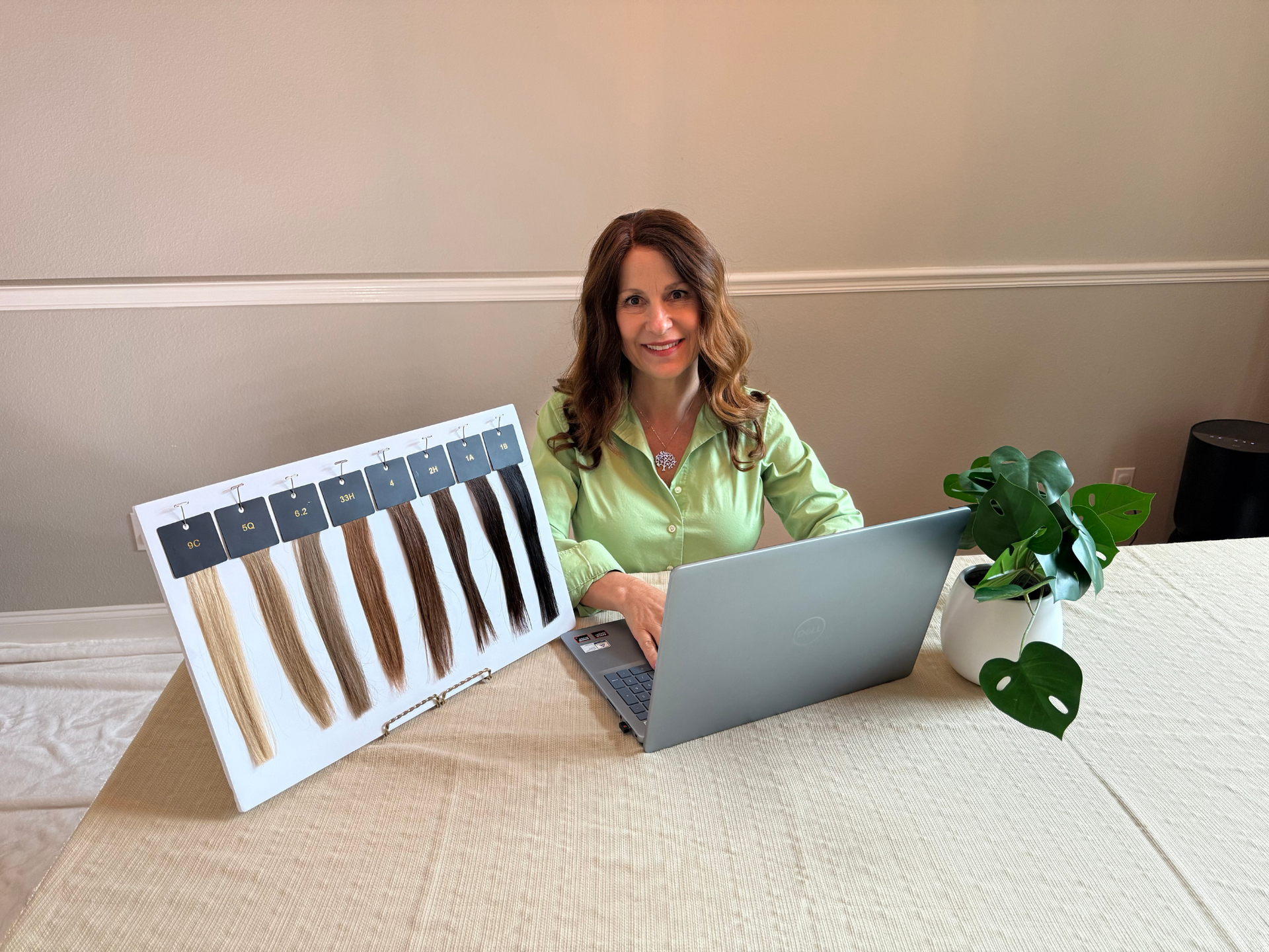 A woman in a navy shirt smiles at two people, possibly in a business setting with a window and a framed print.
