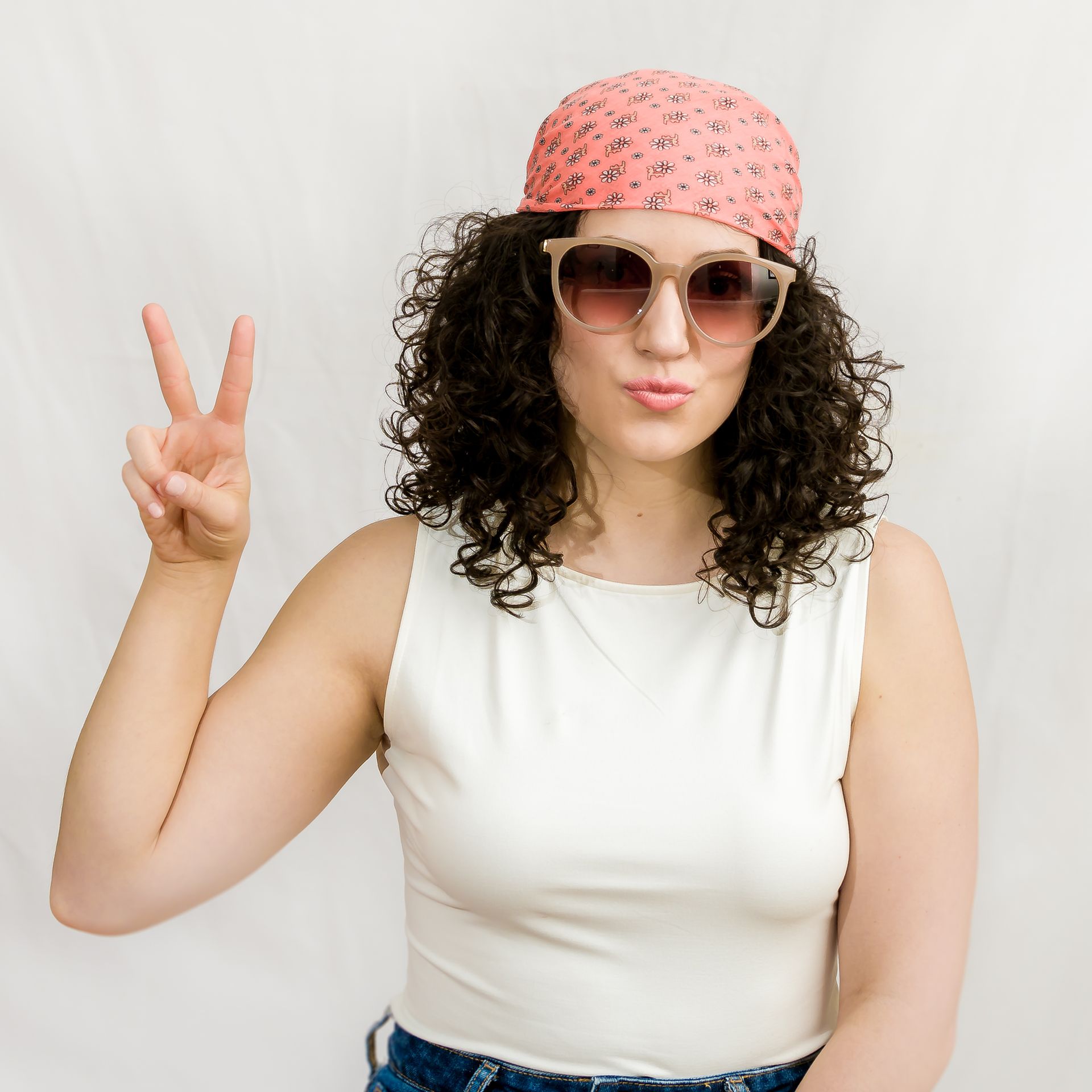 Woman comparing hair swatches, selecting a color. White room setting with a mirror and greenery.